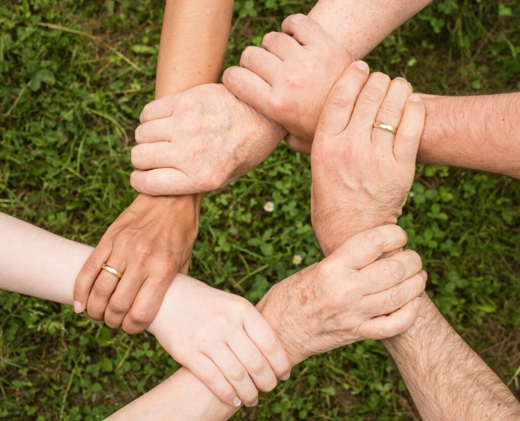 pexels-photo-461049-461049 Close-up of diverse hands forming a connection, symbolizing teamwork and unity outdoors.